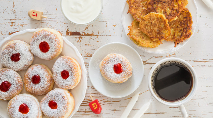 Aerial view of a Hanukkah table topped with latkes sufganiyot and dreidels